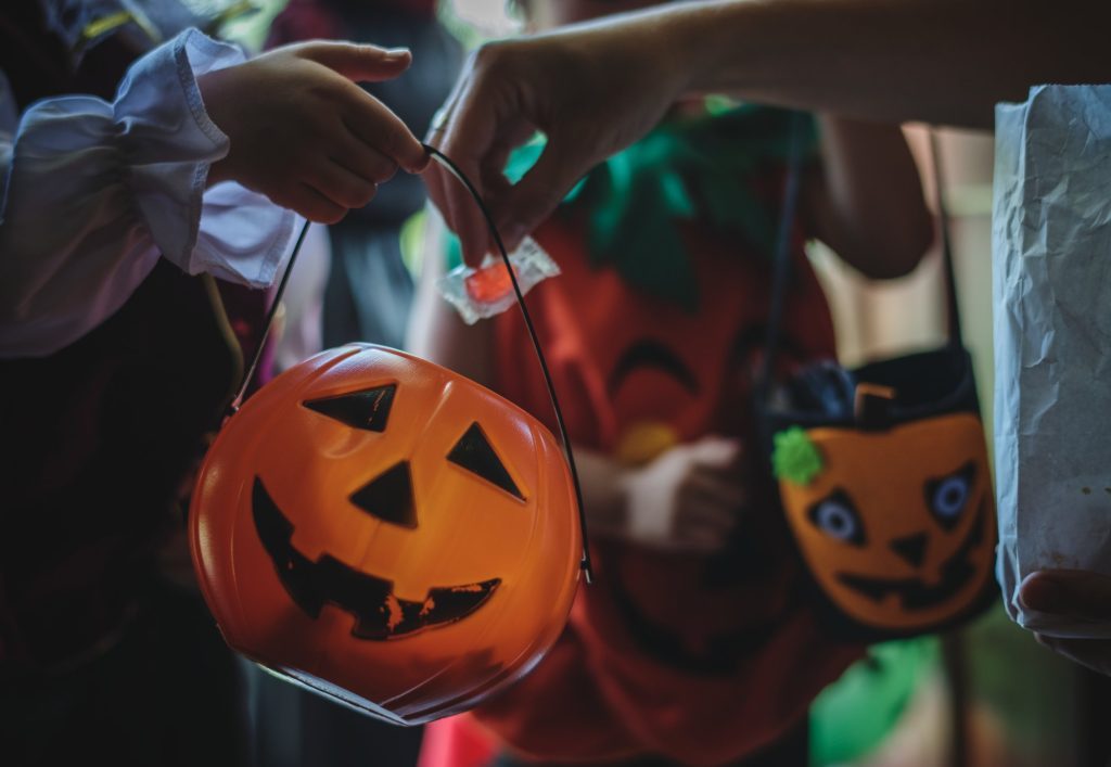 Adult putting candy in a trick-or-treater’s bucket.