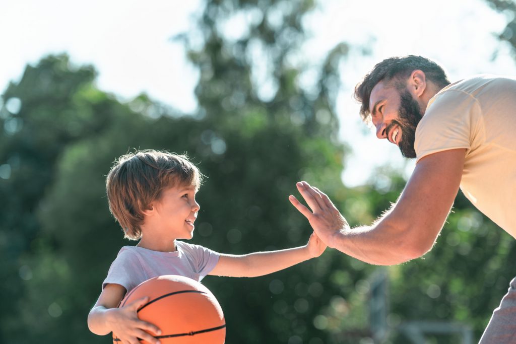 father and son high-fiving during a game of basketball