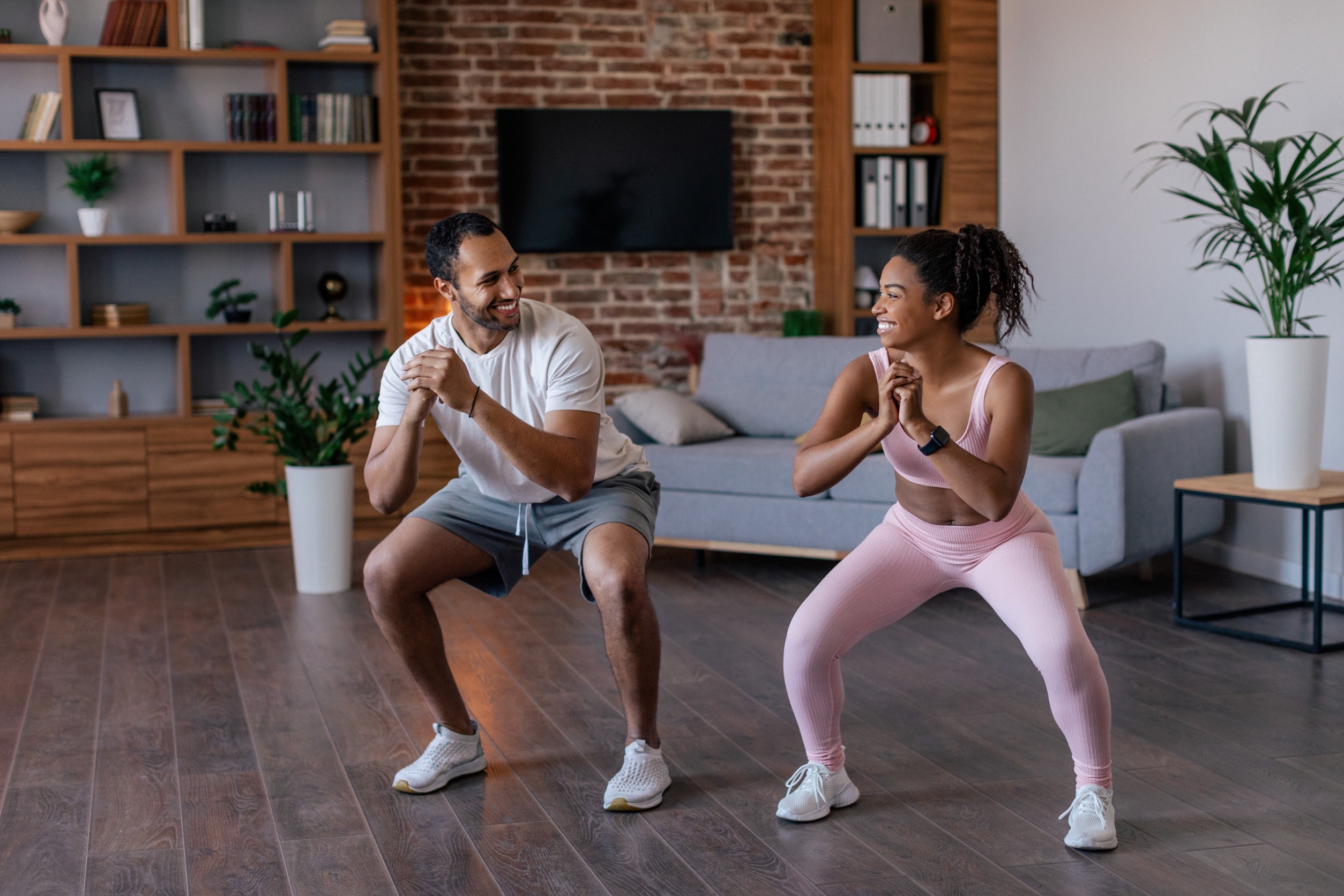 Couple doing a partner workout squatting next to each other.