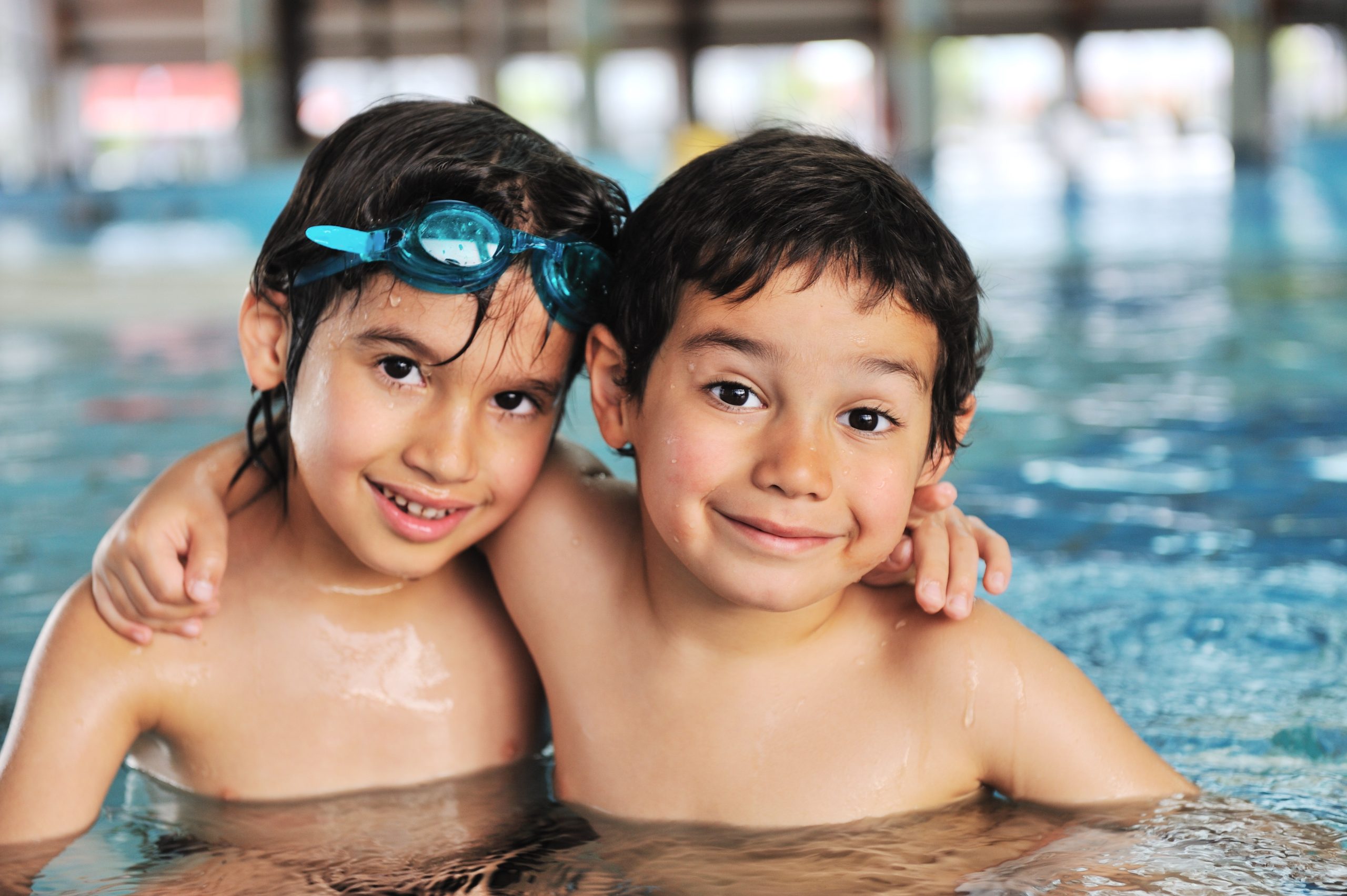 Two boys in swimming pool smiling at camera