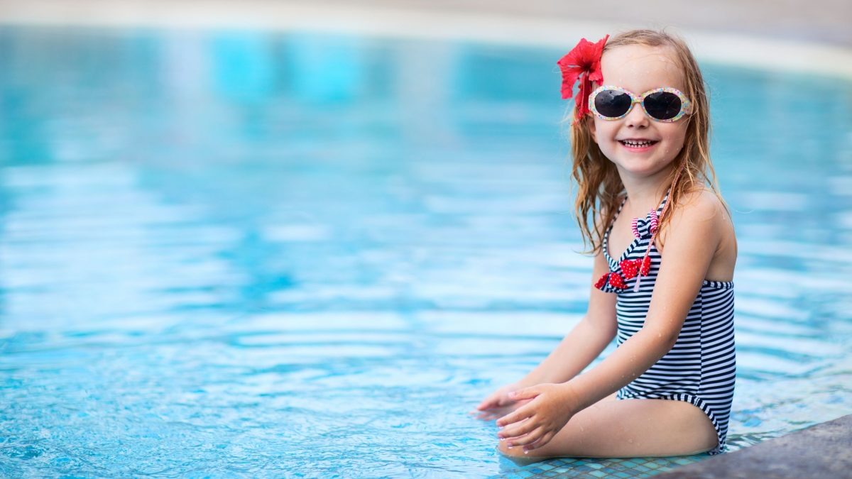 a cute little girl with sunglasses at the pool