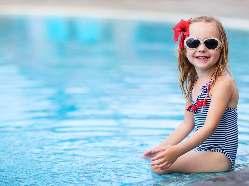 a cute little girl with sunglasses at the pool