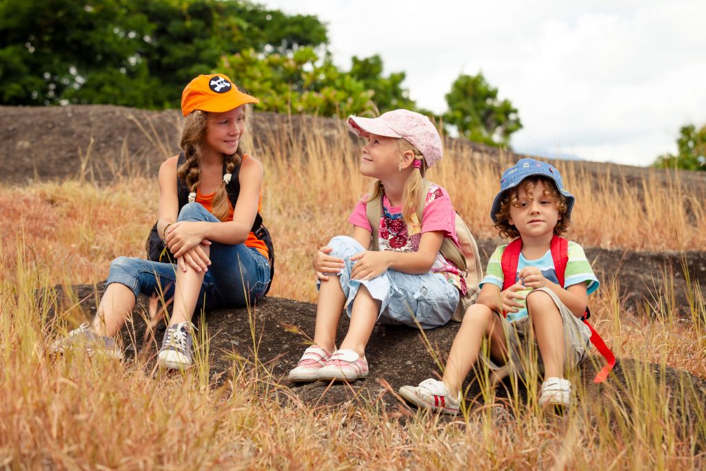 three young children with backpacks becoming friends at summer camp