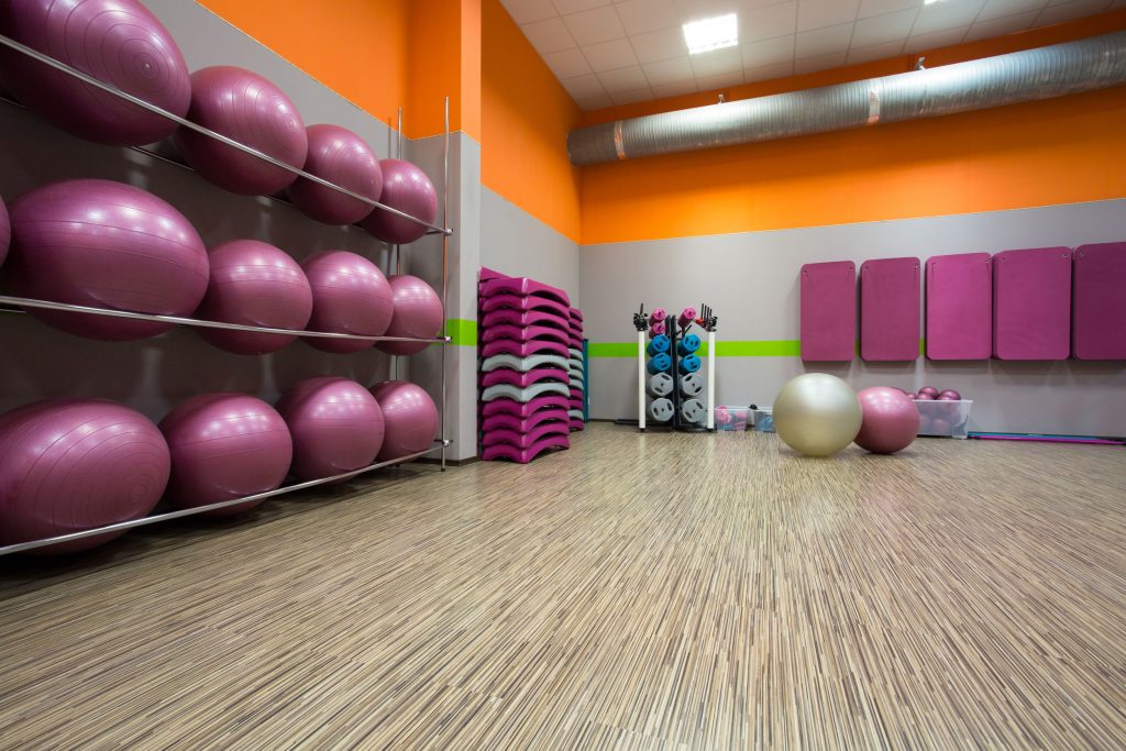 brightly colored group fitness room with exercise balls, mats, and weights