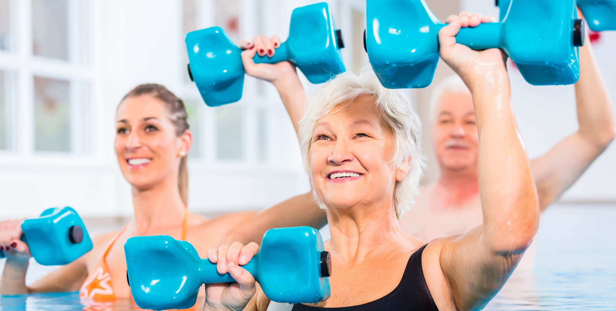 senior man and woman using small weights to tone muscles in the pool