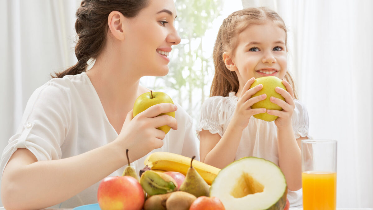 a mom and her daughter eating fresh fruit