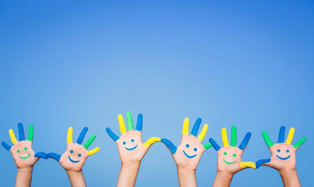 three pairs of children’s hands with smiley faces painted on them