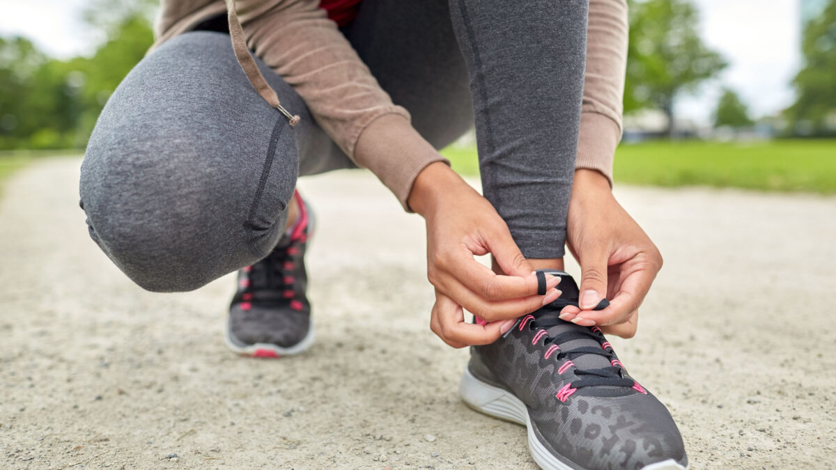 a woman tying her shoelaces before running outside in the spring