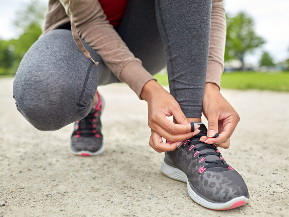 a woman tying her shoelaces before running outside in the spring