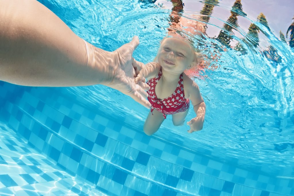 young girl swimming to her mom underwater at the Y pool