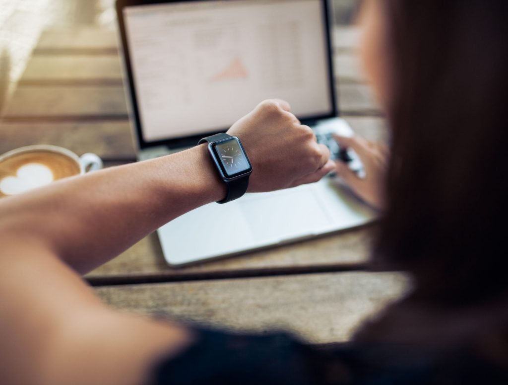 young woman checking her watch as she works at a computer