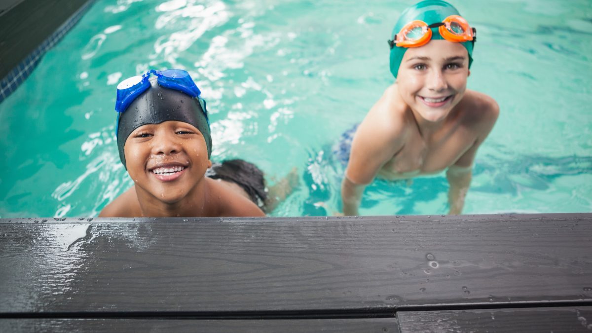 Two boys in swimming pool smiling at camera