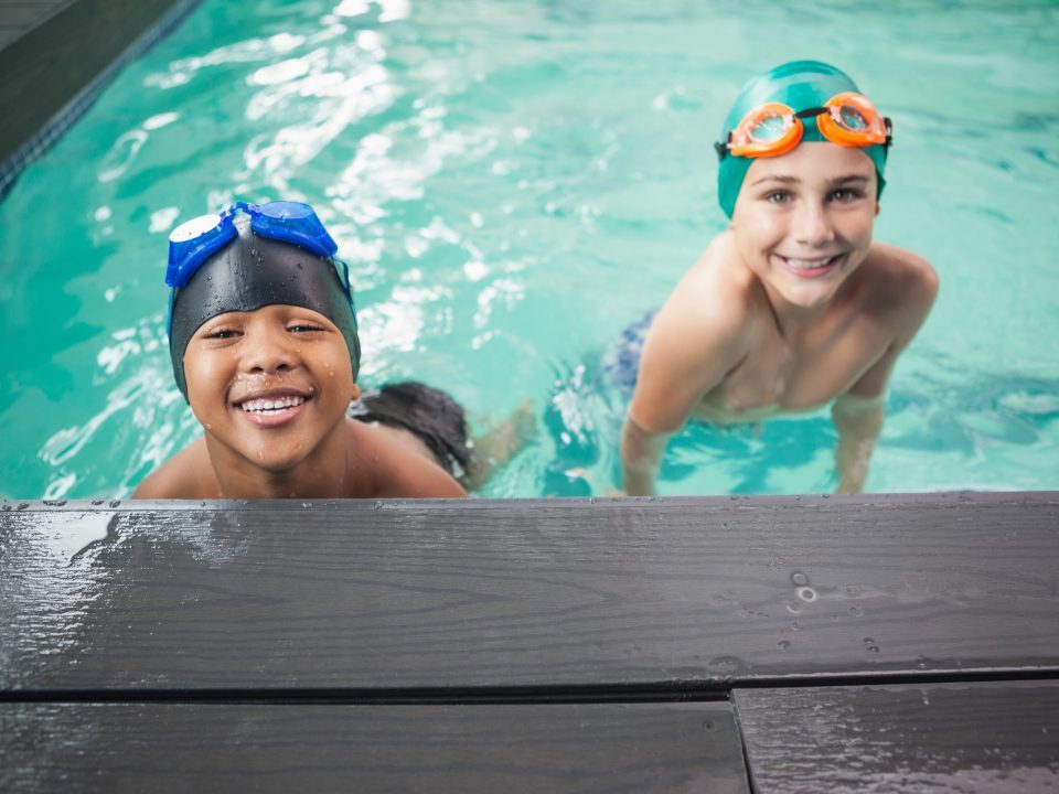 Two boys in swimming pool smiling at camera