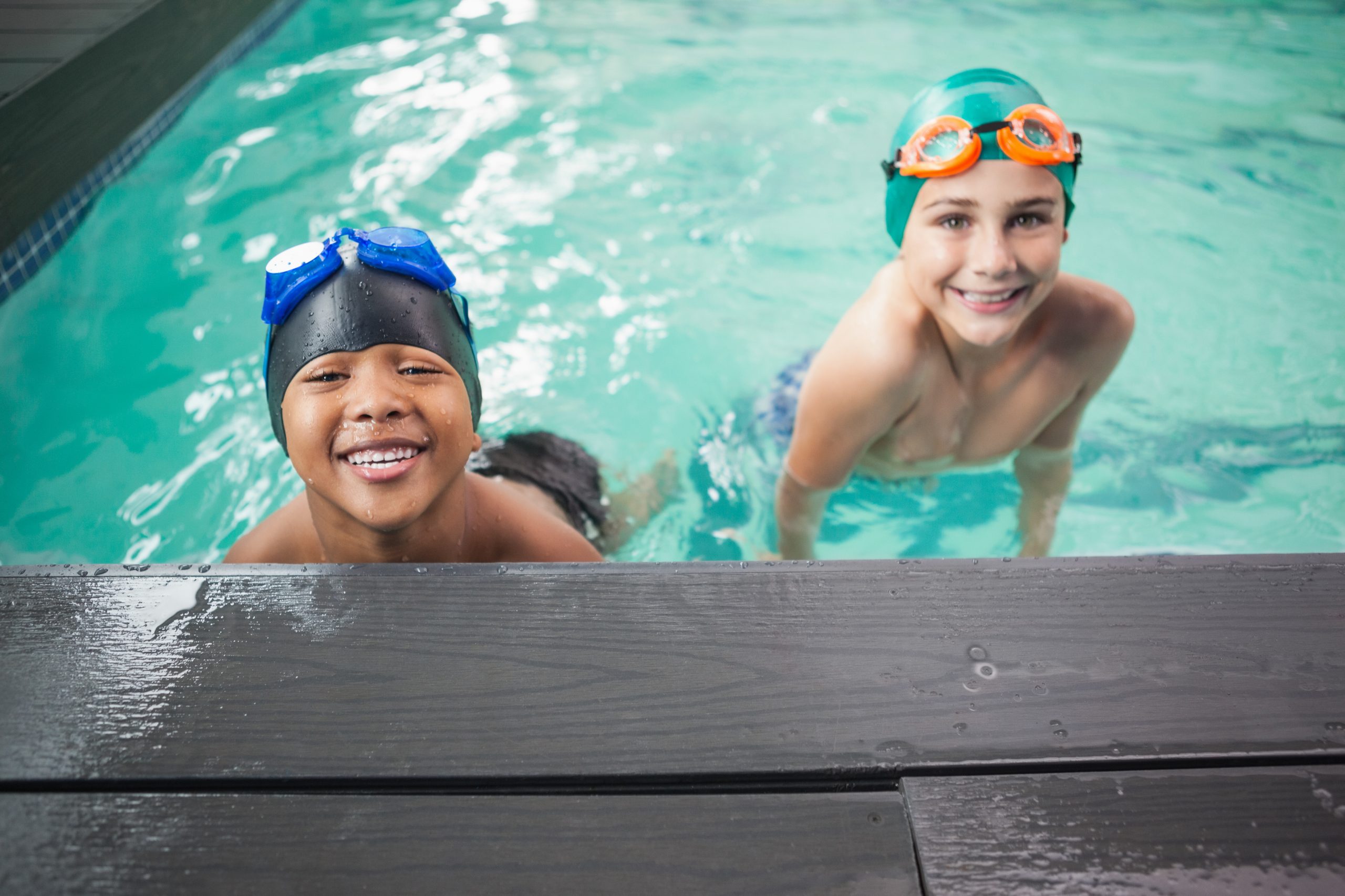 Two boys in swimming pool smiling at camera