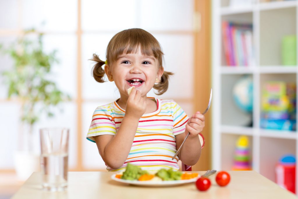 Alt: cute little girl eating broccoli, tomatoes, carrots, and other vegetables