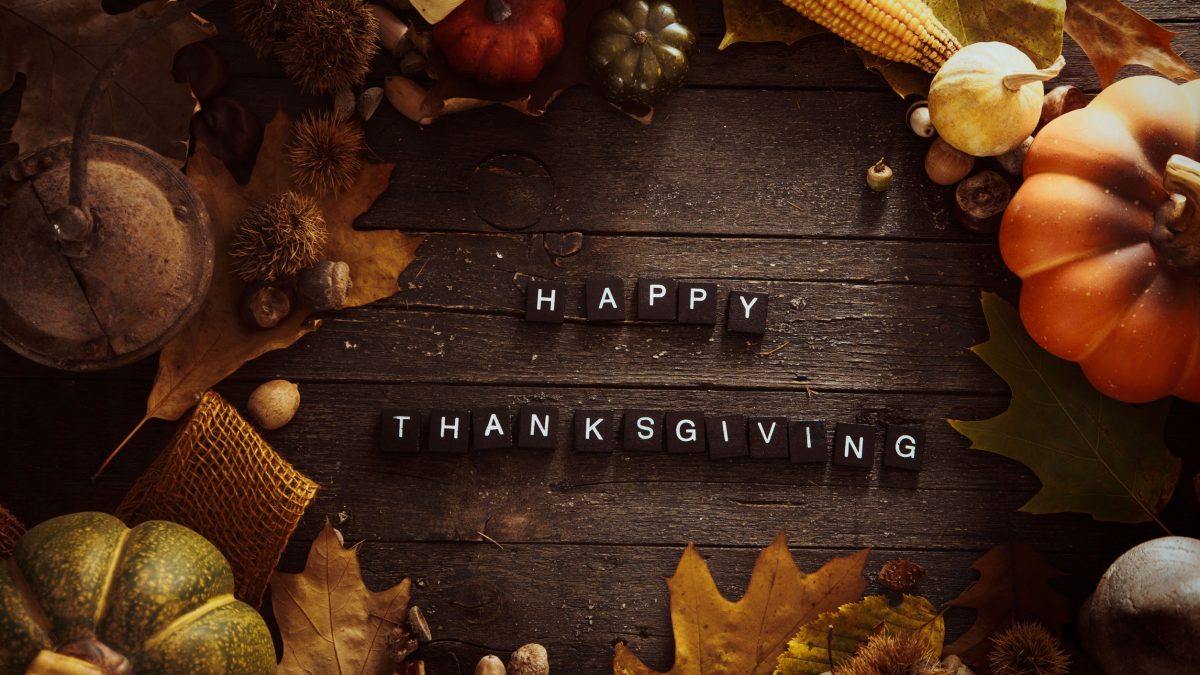 fall fruits and vegetables on a wooden table with “Happy Thanksgiving” letters