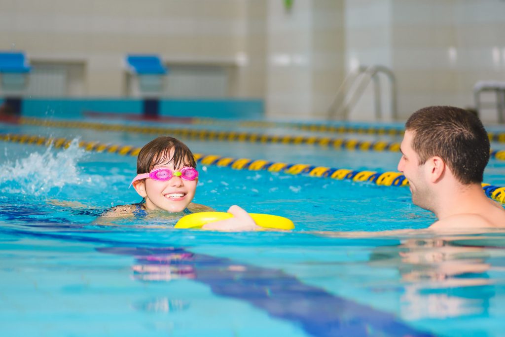 girl swims to the instructor during a private lesson