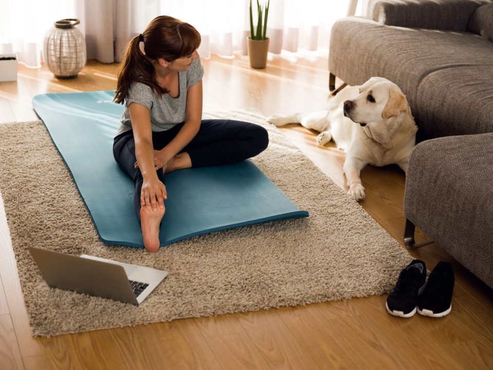 a woman stretching in her living room next to her dog